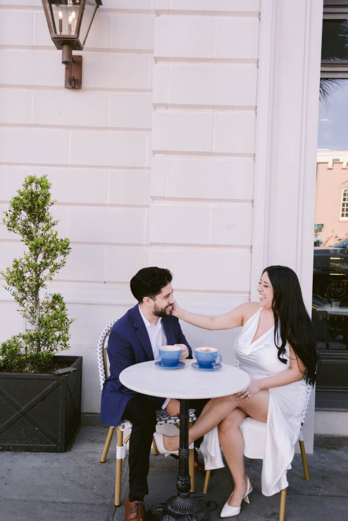 bakery engagement photos of man and woman in white dress and tux 
coffee shop engagement photos with mugs and coffee, girl in white dress in charleston scluxury wedding photographer charleston