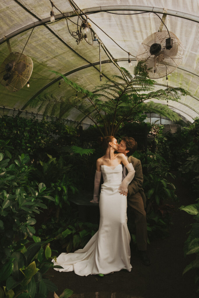 documentary wedding photography of couple in green house kissing on wedding day