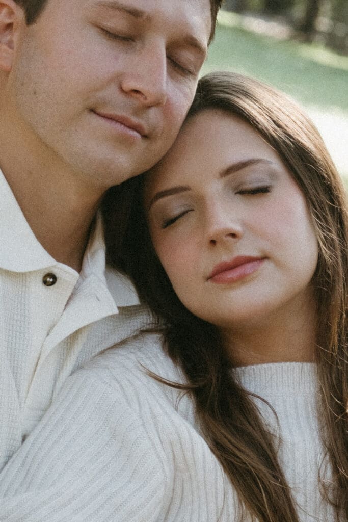 couple guy and girl faces close up eyes closed like film outside hampton park engagement photoshoot