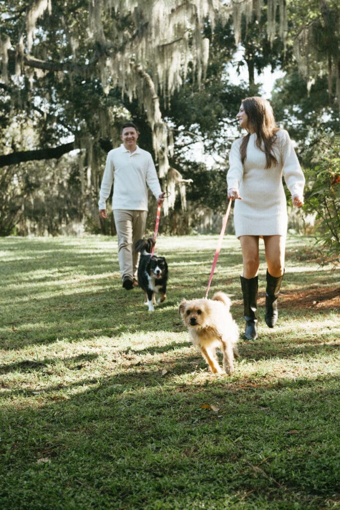 engagement shoot documentary style candid of couple outside under tree with dogs  hampton park engagement photoshoot