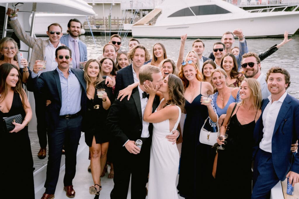 bride and groom kissing on boat with friends