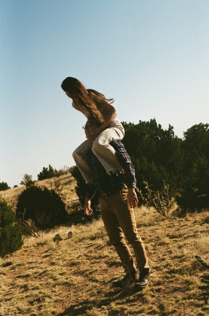 girl on guys shoulders engagement photo in moutains