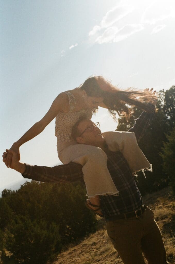 girl on guys shoulders engagement photo in moutains