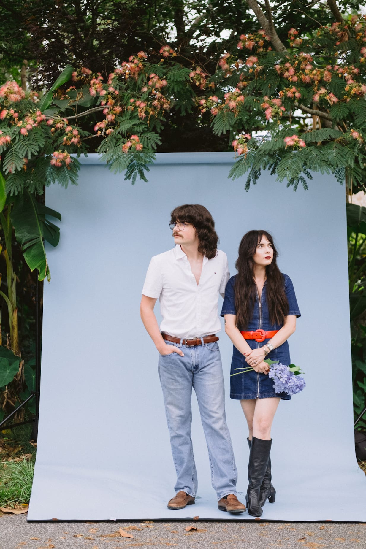 couple with blue background outside with plants 70s vintage vibe engagement photoshoot ideas