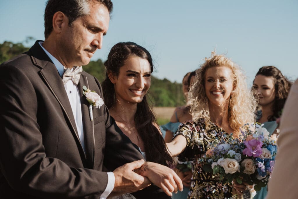 candid shot of bride being given away by father during ceremony at cotton dock at boone hall plantation