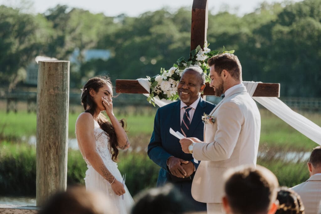 candid shot of bride and groom during ceremony at cotton dock at boone hall plantation