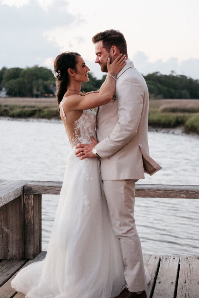 Candid wedding moment at Boone Hall’s Cotton Dock at sunset of bride and goom