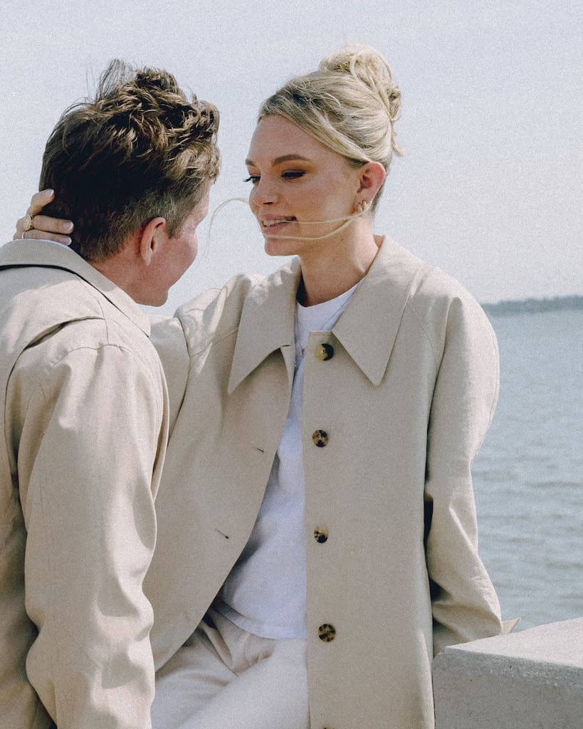candid engagement photo of couple holding each other with water in background at battery park