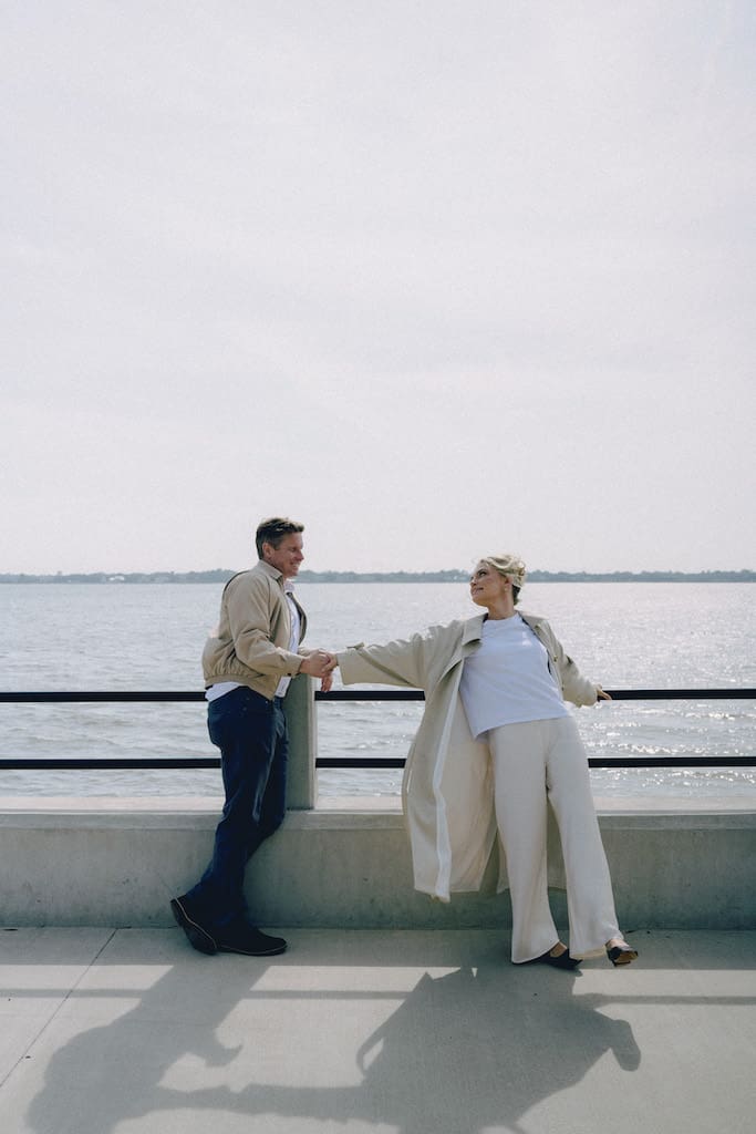candid documentary style photo of couple reaching for each other with water in background at battery park charleston sc