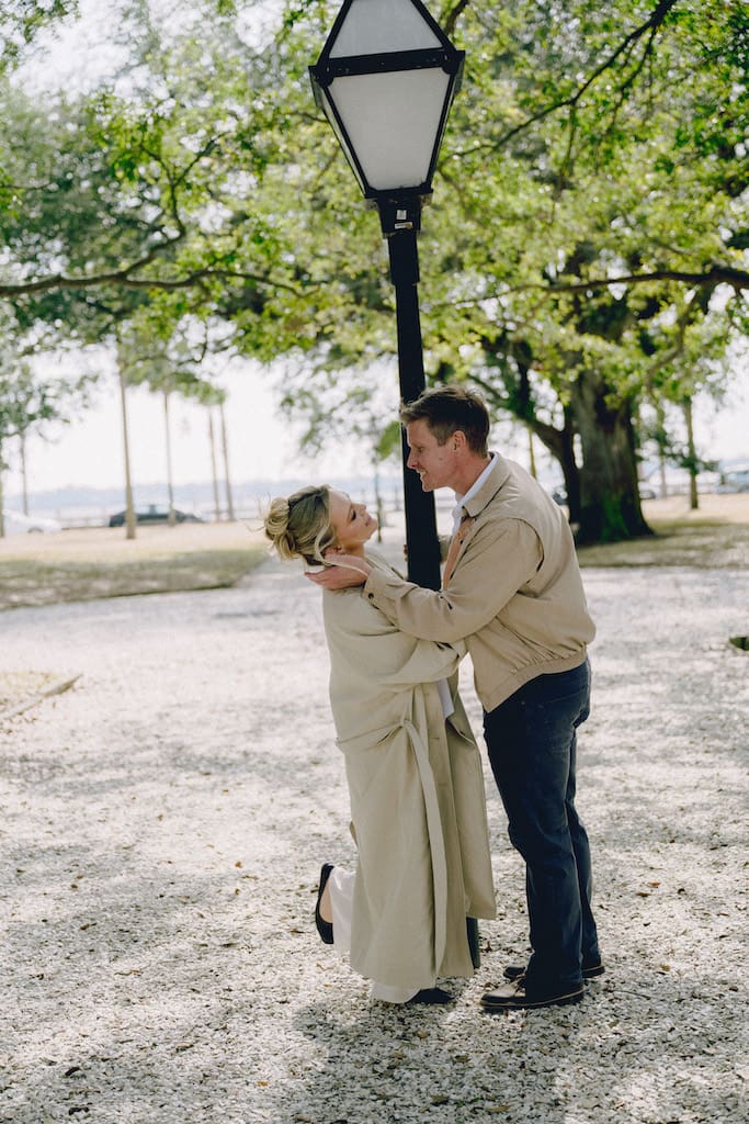 candid photo of engagement shoot at battery park and white point gardens, couple swinging around lamp post