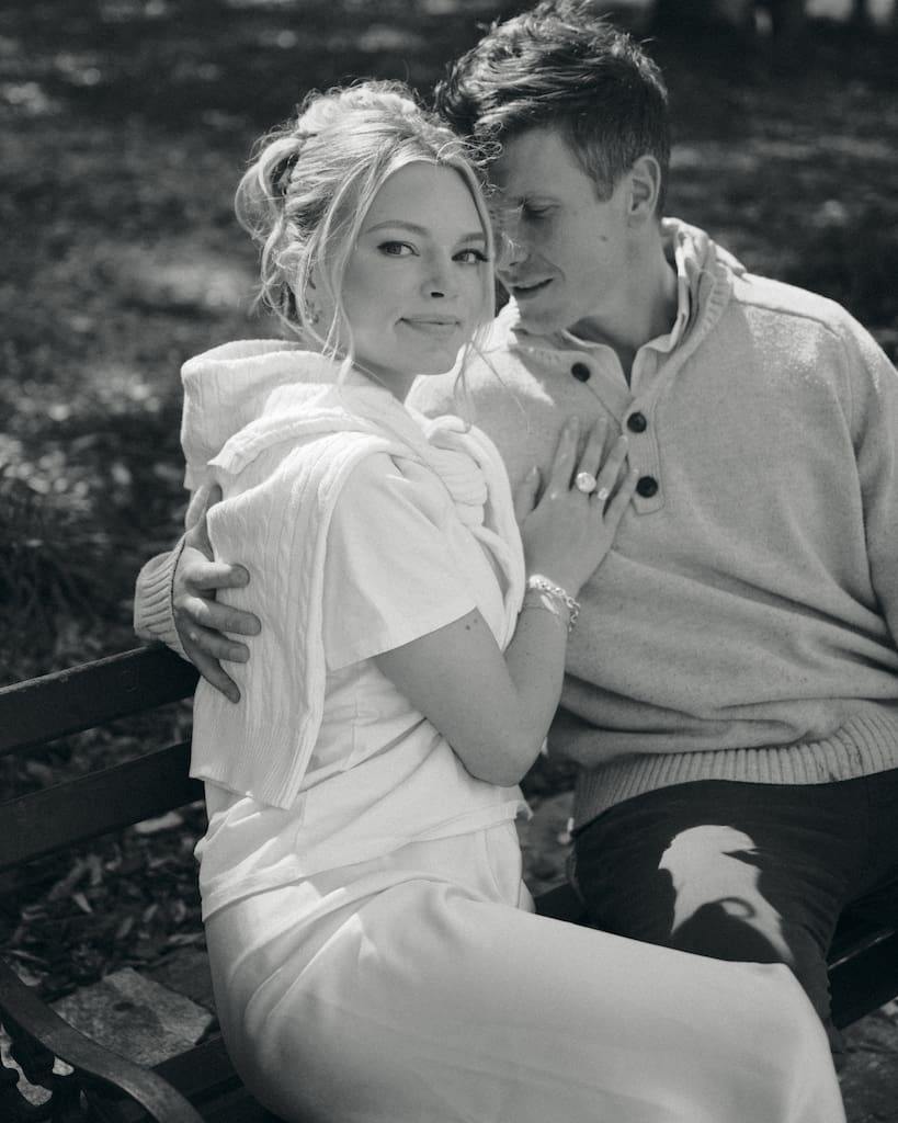 portrait of couple for engagement shoot at the battery in downtown charleston sitting on park bench under trees