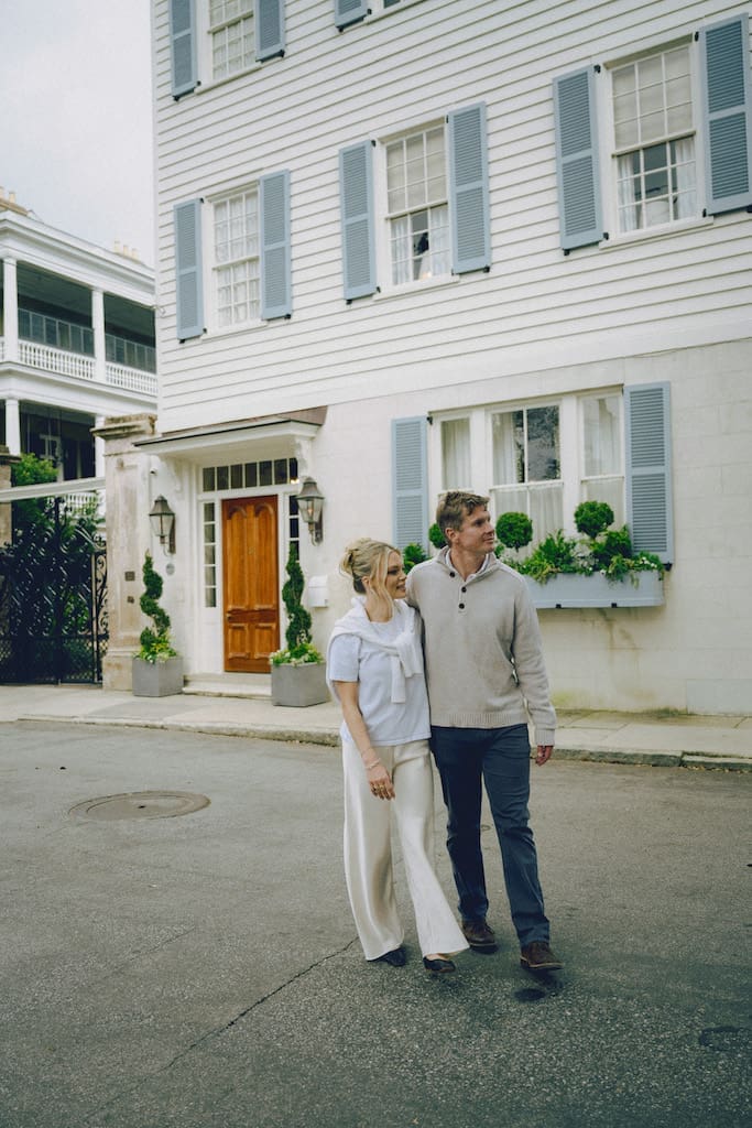 engagement shoot inspo of couple walking with historic charleston houses