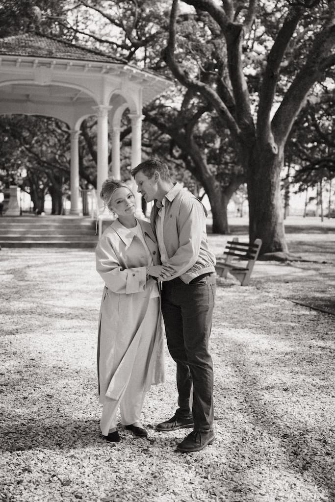 black and white photo of couple candidly posing in front of gazebo at white point gardens downtown charleston