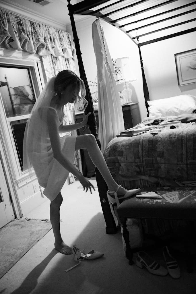 candid getting ready black and white photo of bride with shoes