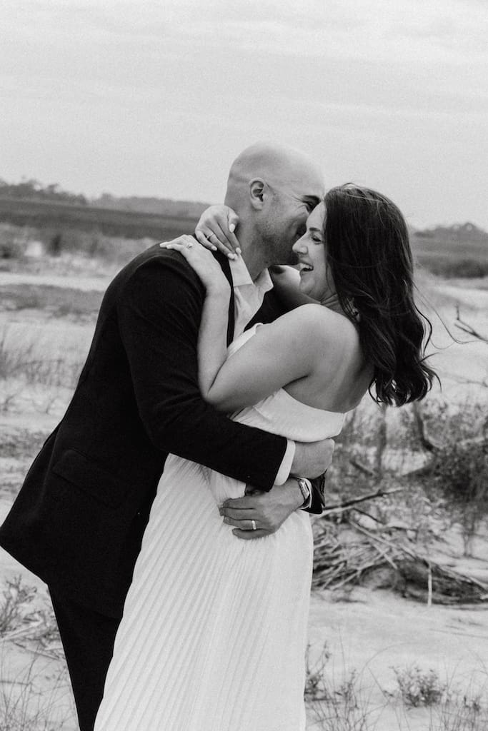 candid black and white portrait of couple on their wedding day on beach laughing