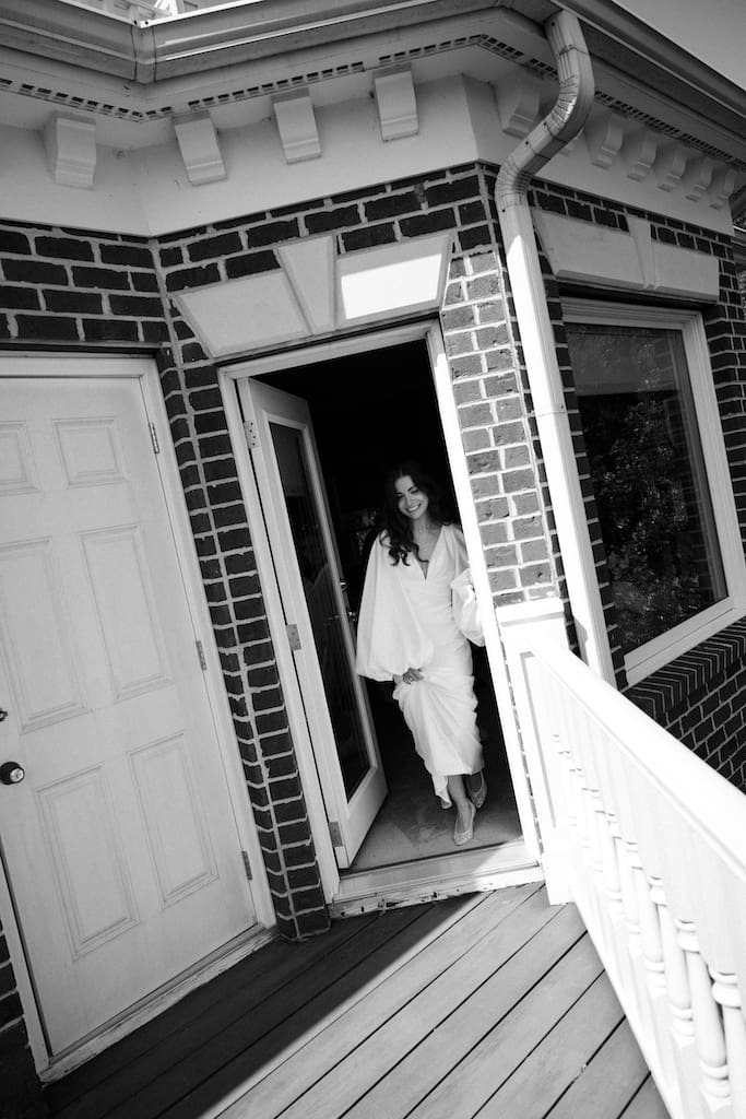 first look moment of bride walking out of a door in black and white