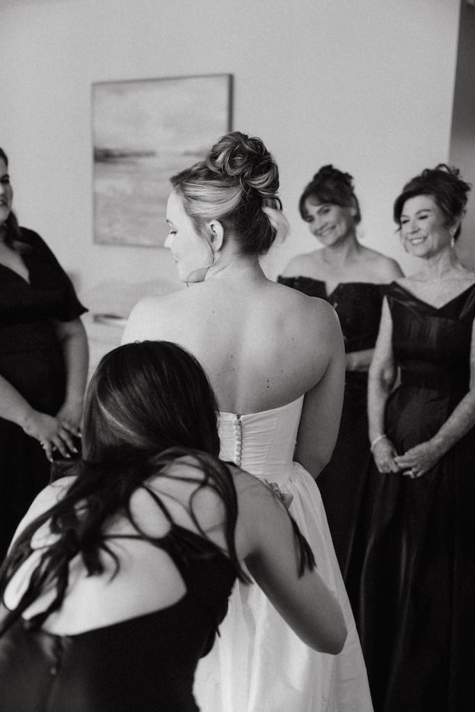 bride getting in dress with friends and family in black and white