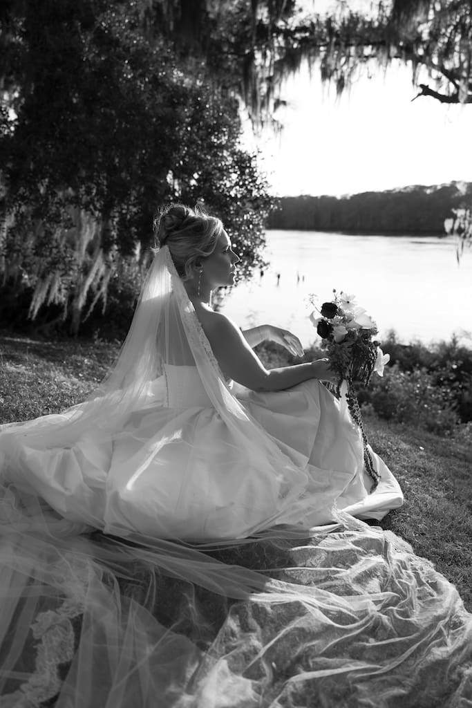 black and white bridal portrait with veil and flowers on the water with oak trees at kimbels in pawleys island sc